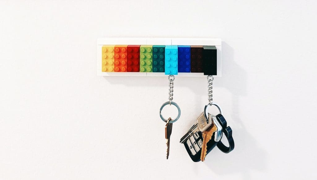 Key rings attached to Legos hang from a Lego wall hanging.