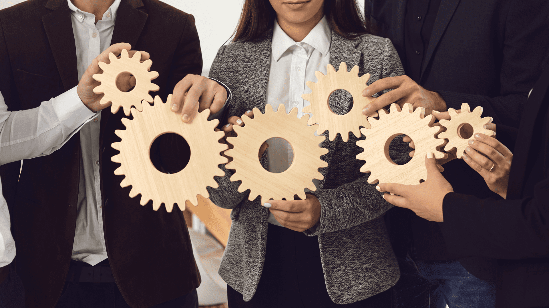 A group of people hold wooden gears together.